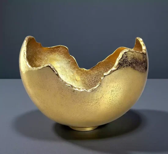 Textured gold metal bowl with artistic broken eggshell edge design.