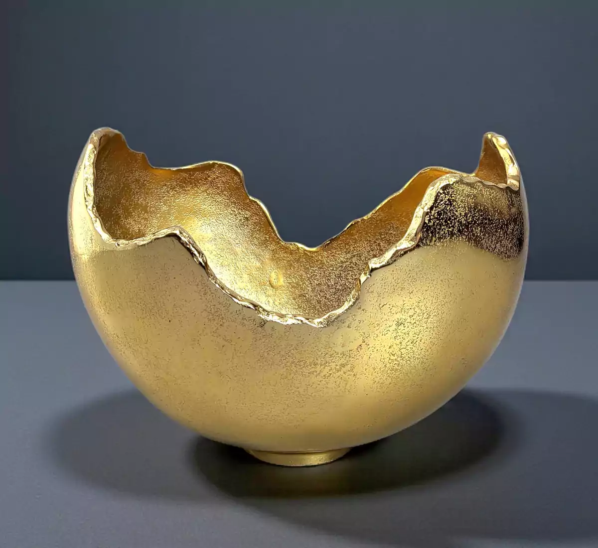 Textured gold metal bowl with artistic broken eggshell edge design.