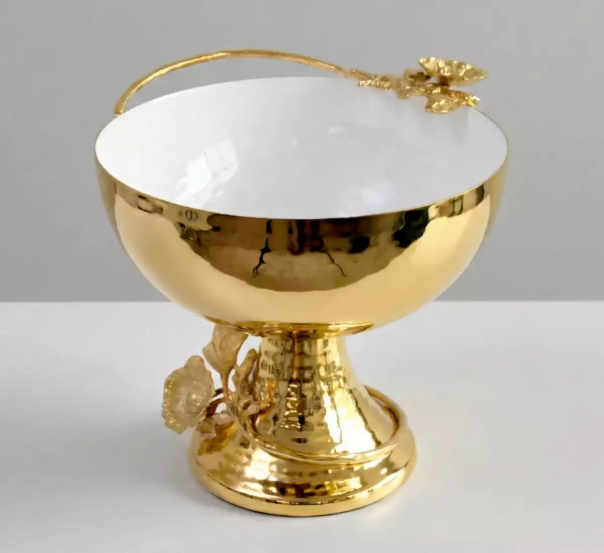 Luxury gold footed bowl with white enamel inside and floral vine handle.