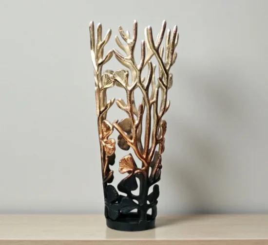 Modern cylindrical metal vase with gold to black gradient finish and branch design.